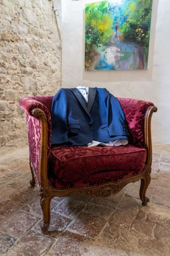 A vertical shot of a blue suit on a red old-fashioned chair waiting for the groom to put it on