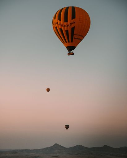 A vertical shot of three hot air balloons flying over Luxor, Egypt