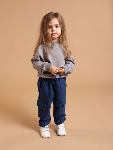 A little Caucasian girl posing on isolated brown background