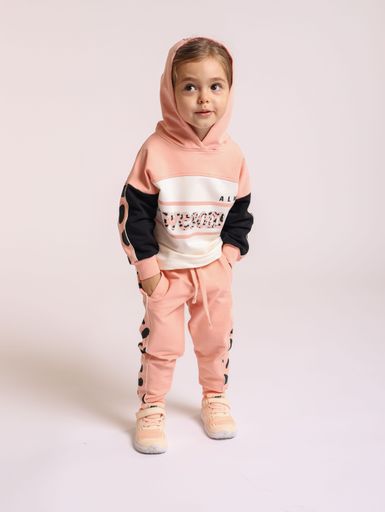 A little Caucasian girl in sportswear posing on isolated white background