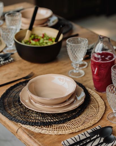 A vertical high angle aesthetic shot of empty plated and glasses on a wooden table with a salad