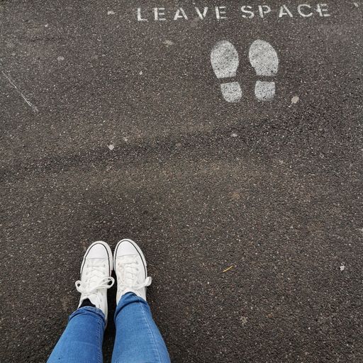 A top view of shoes on the pavement with spots for standing and social distancing- the new normal concept
