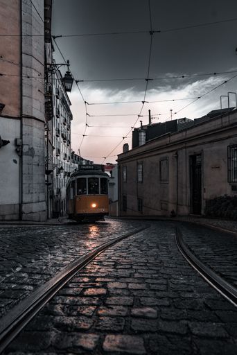 A vertical shot of a tram through the streets of Lisbon on a cloudy day
