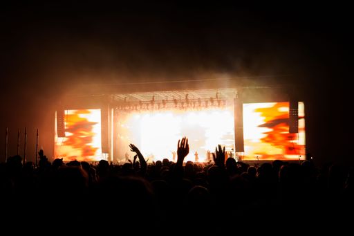A beautiful shot of a crowd of dancing people near an outdoor illuminated orange stage