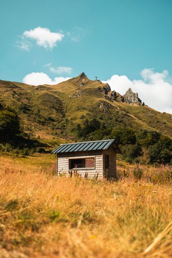 A vertical shot of a small cabin with the Puy de Sancy mountain in the background