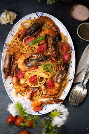 A large plate of Spaghetti allo Scoglio on beautifully decorated table - food aesthetic concept