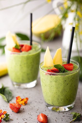 A glass of kiwi smoothie with straw on beautifully decorated table - food aesthetic concept