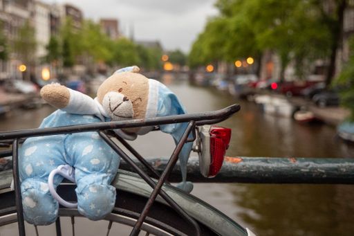 A closeup shot of an old bicycle with a teddy bear on the bridge