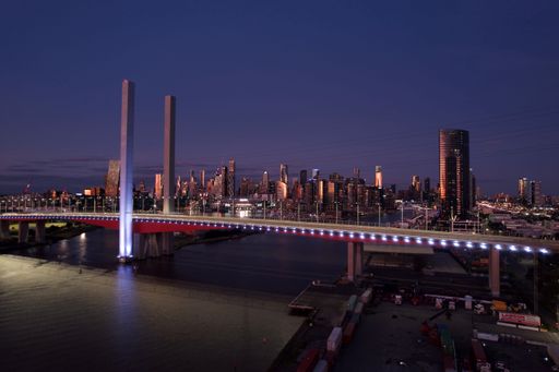 A drone shot of the Bolte Bridge and the cityscape of Melbourne under dark dusk sky after sunset, Australia
