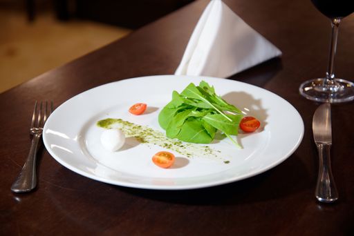 A high angle shot of a white plate of salad with cherry tomatoes