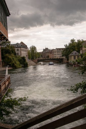 A vertical shot of a canal next to buildings under a dark gloomy sky in Strasbourg