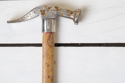 A top view shot of a hammer on white wooden planks