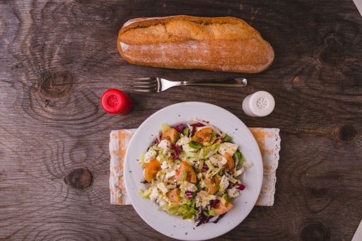 A top view of a delicious gourmet vegetable salad on a table with salt, pepper, and bread