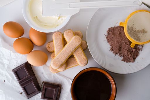 A closeup shot of a kitchen table with ingredients to make tiramisu
