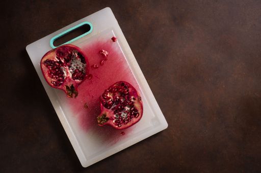 A top shot of a juicy grenade sliced into two parts on the board with a wooden table in the background