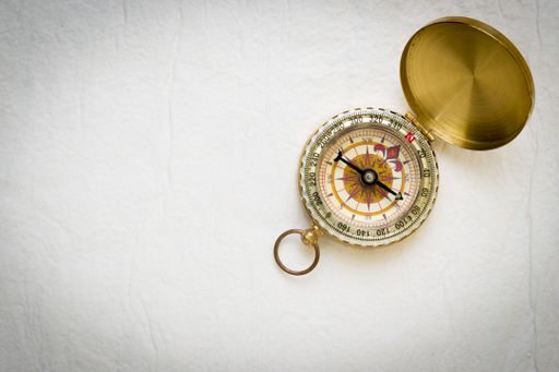 A top closeup of a vintage compass on the white background