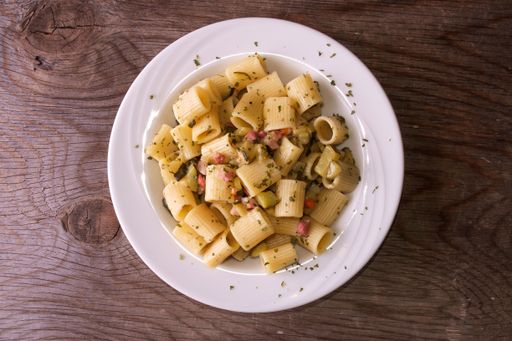 A top view of rigatoni pasta with bacon and zucchini
