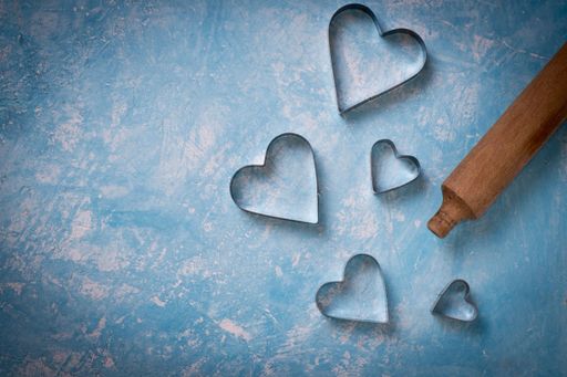 A top view of a wooden pin and heart-shaped metals used for baking