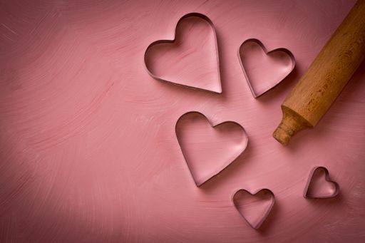 A top view of a wooden pin and heart-shaped metals used for baking