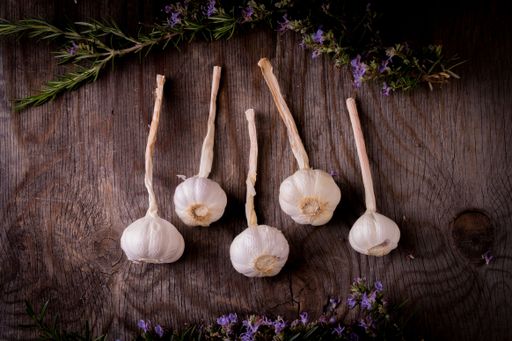 A top view of garlic and rosemary on a wooden table