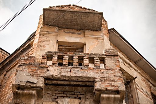 A low angle shot of an old, abandoned brick building with weathered walls