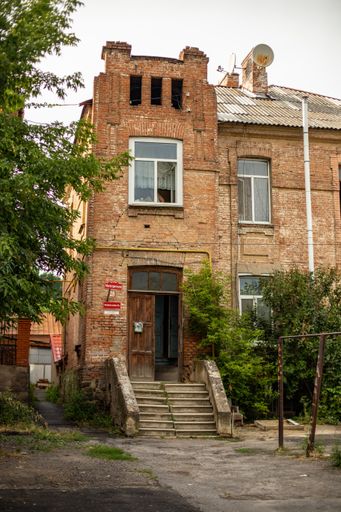 A vertical shot of the facade of an old, brick building surrounded with trees