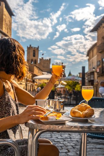 A vertical shot of a lady having breakfast in a cafe near a castle in Navarra, Spain