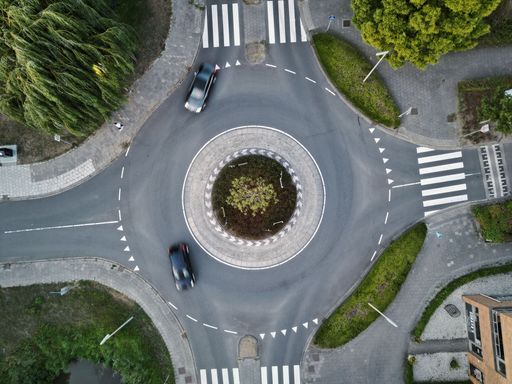 An aerial view of a traffic roundabout, roads, lanes with cars.