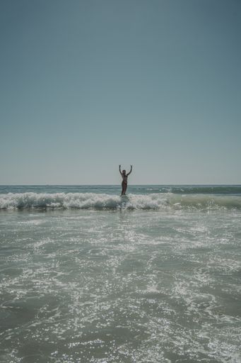 A vertical shot of a Caucasian woman in bikini surfing at a beach in Cadiz, Andalucia, Spain