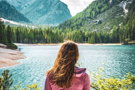 A young caucasian lady admiring the view of Baires Lake in the Dolomite mountains, South Tirol, Italy, Europe