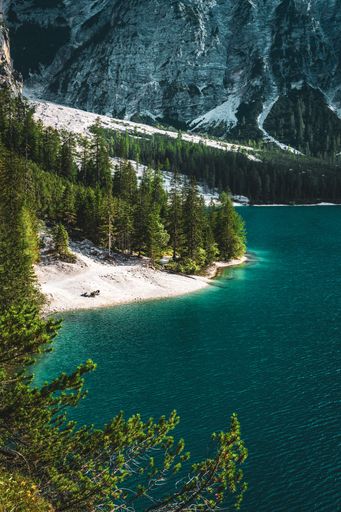 A vertical shot of people enjoying the turquoise water on the shore of Baires Lake in the Dolomites, South Tirol, Italy