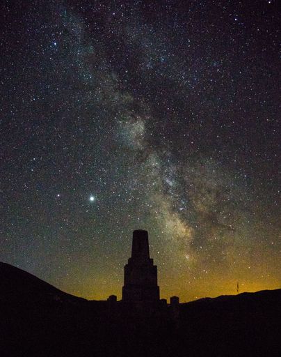 Above the dark old monument silhouette night sky with stars and milky way on it.