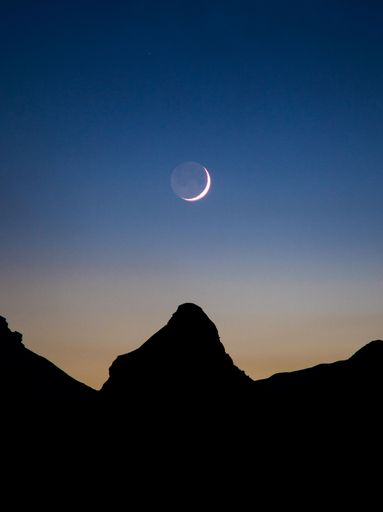 The waxing crescent moon over mountain silhouette
