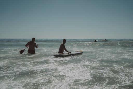 A closeup shot of people in the water with a surfing board