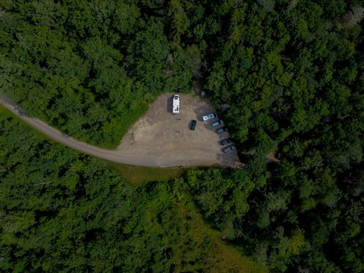 An aerial view of parked cars in the middle of lush green forest