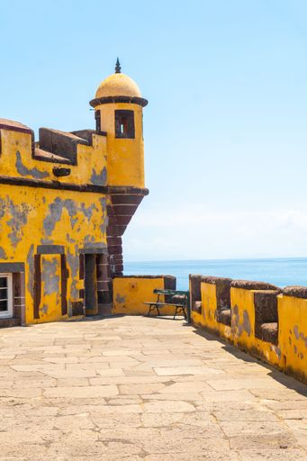 A vertical shot of the old yellow watchtower at the Forte de Sao Tiago beach of Funchal, Madeira
