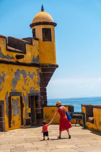 A vertical shot of a mother and son near the old watchtower at Forte de Sao Tiago, Funchal, Madeira