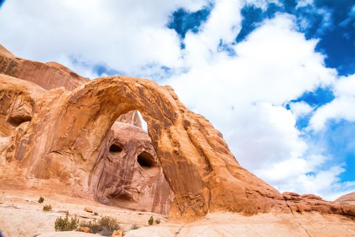 A low angle shot of a face-like rock formation through the Corona arch in Moab, Utah