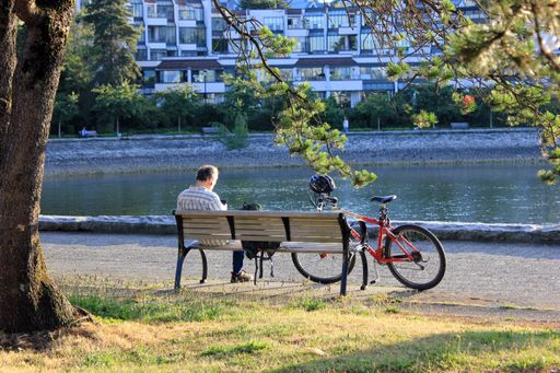 A man reading a book sitting on a bench at seaside in Vancouver