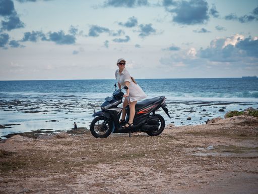 A female sitting on motorcycle in background of sea
