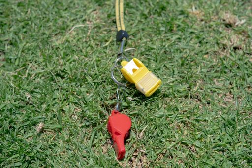 A closeup shot of football whistles on a filed lawn