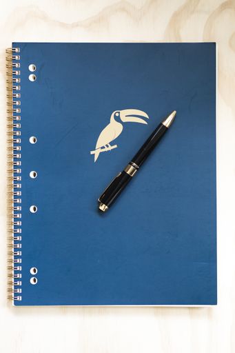 A top view of a blue copybook with a pen on it