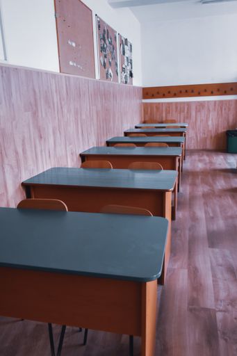 A vertical shot of a raw of tables and chairs in a classroom