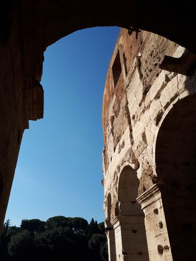 A vertical shot of an old historical building and a sky through the arch in Rome