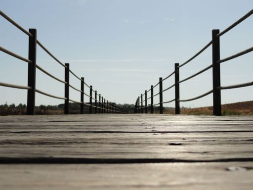 A low-angle shot of the wooden floor of the narrow bridge