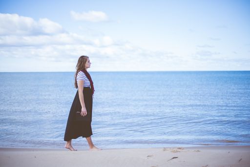 A beautiful shot of a female walking on the beach shore while holding the bible