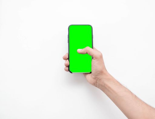A man's hand holding his smart phone with green screen on a white isolated background