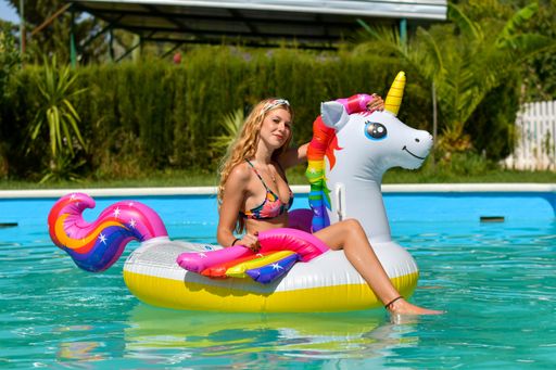 A closeup shot of a beautiful young lady in the pool on an inflatable unicorn