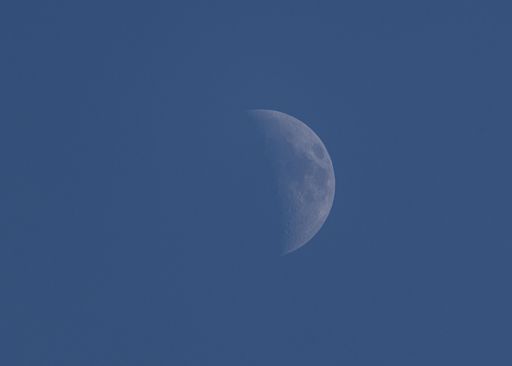 A closeup shot of a moon rising in the late afternoon sky