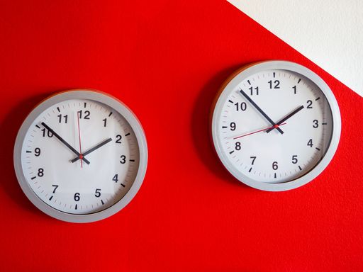 A closeup shot of two white clocks on the red  wall